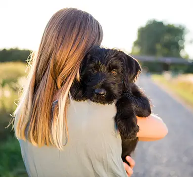 Frau mit ihrem Hund auf dem Arm
