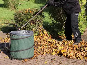 Laub auf dem Gehweg wird zusammengekehrt
