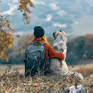 Wanderung mit dem Hund Frau macht auf dem Hügel eine Wanderpause mit ihrem Hund
