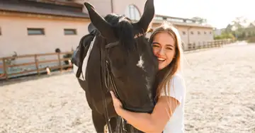 Pferdehaftpflicht eine junge Frau umarmt den Kopf ihres braunen Pferdes