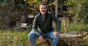 Ralf Becker auf einer Bank in seinem Naturgarten