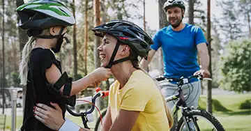 Mit dem Fahrzeug unterwegs Familie setzt vor der Radtour Fahrradhelme auf