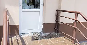 Alles über die private Haftpflicht Fußball liegt zwischen den Scherben vor der kaputten Glasscheibe