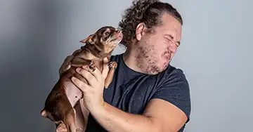 Mann ekelt sich vor seinem Hund mit Mundgeruch