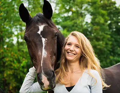 Junge Frau mit ihrem Pferd auf der Weide
